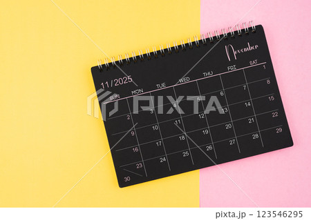 November 2025 Black calendar spiral on yellow and pink background. November 2025 Black calendar spiral on yellow and pink background. 123546295