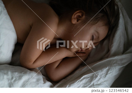 Young boy sleeps soundly at home, wrapped in blankets, exuding a sense of warmth and tranquility. 123546542