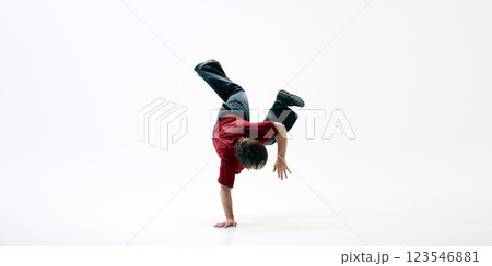 Dancer performing one-handed handstand, body in perfect control, and his legs bent in motion against white background. Dancer performing one-handed handstand, body in perfect control, and his legs bent in motion against white background. 123546881