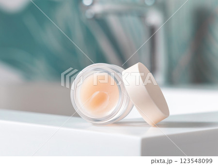 Opened white blank lip balm jar on wash basin in green tropical bathroom close up, cosmetic mockup Opened white blank lip balm jar on wash basin in green tropical bathroom close up, cosmetic mockup 123548099