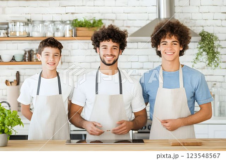 Three sons actively participating in kitchen preparations during a family cooking session 123548567