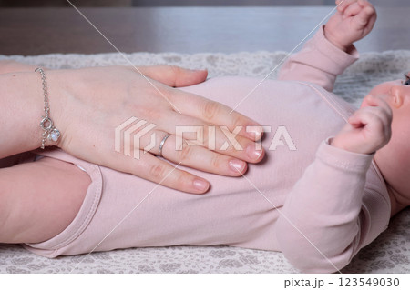 Loving young mother making massage to cute newborn baby on table. Infant health and strengthening exercises at home. Loving young mother making massage to cute newborn baby on table. Infant health and strengthening exercises at home. 123549030