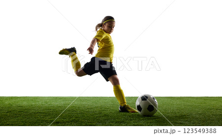 Confident girl in sports uniform controlling ball with precision, playing soccer on grassy surface against white studio background Confident girl in sports uniform controlling ball with precision, playing soccer on grassy surface against white studio background 123549388