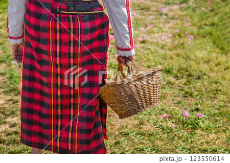 Traditional Bulgarian woman in a red folk costume holding a wicker basket during a cultural festival. Symbolic scene of Bulgarian rose harvest, heritage, rural traditions 123550614