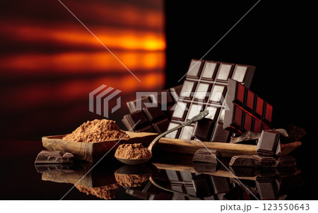 Broken bitter chocolate bars and wooden dish with cocoa powder. 123550643
