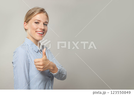 Happy blond young adult business woman wearing shirt showing thumb up on white background Happy blond young adult business woman wearing shirt showing thumb up on white background 123550849