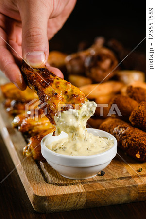 Chicken wing dipped in creamy garlic sauce close-up. Chicken wing dipped in creamy garlic sauce close-up. 123551589