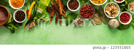 A beautiful collection of colorful spices and herbs, showcasing their natural aromas and vibrant hues on a gentle green background, top view and copy space, banner 123551803
