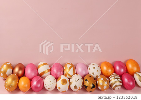 Decorated golden easter eggs on a pink background. Minimal holiday concept. Happy easter background. Creative painting of eggs at home, the idea of simple drawings for coloring, a place for text, a 123552019