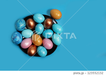 Decorated golden and blue easter eggs on a dark blue background. Minimal holiday concept. Happy easter background. Creative painting of eggs at home, the idea of simple drawings for coloring, a place 123552132