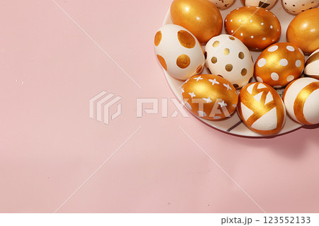 Decorated golden easter eggs on a pink background. Minimal holiday concept. Happy easter background. Creative painting of eggs at home, the idea of simple drawings for coloring, a place for text, a 123552133