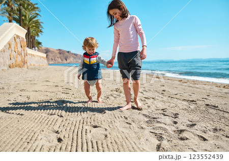 Children Holding Hands on a Sunny Beach Showing Love and Care 123552439