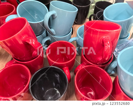 Colorful ceramic mugs arranged on a wooden table at a bustling market Colorful ceramic mugs arranged on a wooden table at a bustling market 123552680