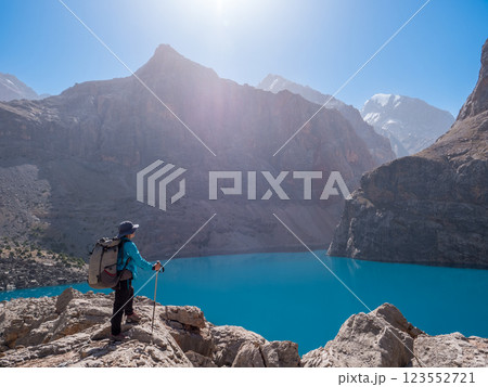 Girl with backpack near lake Big Alo on rocky mountain background. Fann Mountains, Tajikistan, Central Asia 123552721
