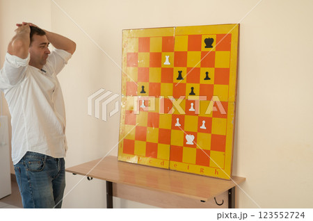Caucasian man standing at wall mounted magnetic chessboard demonstration. Caucasian man standing at wall mounted magnetic chessboard demonstration. 123552724