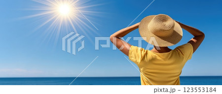 Sunlit straw hat rests against a backdrop of sparkling blue water, evoking the essence of summer relaxation and warmth 123553184