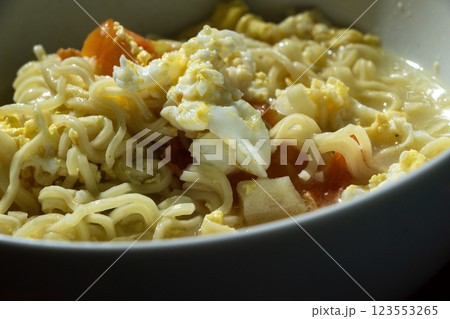 Close-up detail of boiled noodles or yellow noodle soup mixed with egg and tomato 123553265