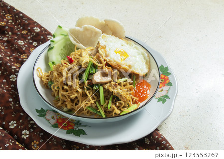 Fried noodles on a round white plate with a brown patterned cloth on a white marble table, Indonesian food, negative space Fried noodles on a round white plate with a brown patterned cloth on a white marble table, Indonesian food, negative space 123553267