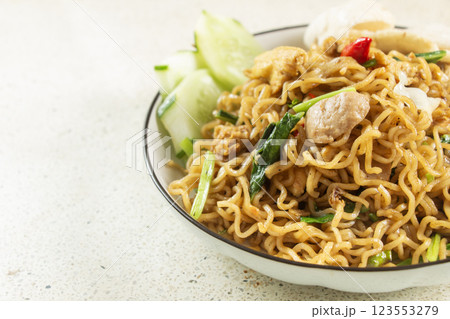 negative space fried noodles with fried egg topping, meatballs, shredded chicken, white marble texture table isolated 123553279