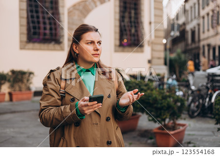 Upset sad, skeptical, serious woman holding smartphone gadget for communicate outdoors. Negative people emotion, Urban lifestyle concept. Angry 30s girl reading bad news 123554168