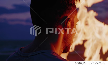 Man observing bonfire flames at dusk 123557405