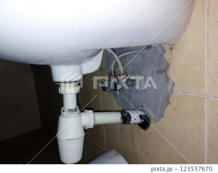 Plumbing Repair in an Urban Bathroom Corner Near the Sink Drain Line and Water Supply Plumbing Repair in an Urban Bathroom Corner Near the Sink Drain Line and Water Supply 123557670