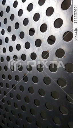 Stainless Steel Mesh Displays Intricate Pattern of Perforations and Reflections in Bright Light 123557694