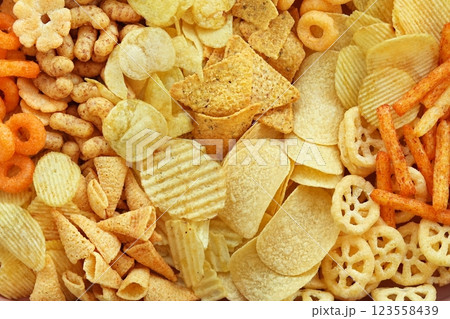 Colorful mix of salty snacks for beer varieties: chips and pretzels, onion rings and crackers. Non-healthy junk food background Colorful mix of salty snacks for beer varieties: chips and pretzels, onion rings and crackers. Non-healthy junk food background 123558439