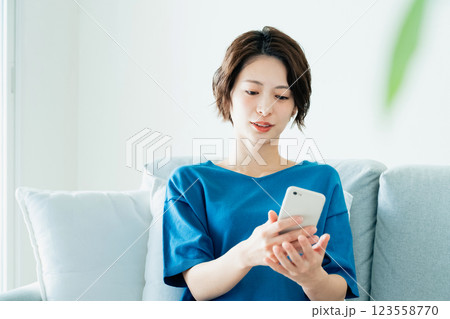ソファでスマホを見る若い女性 ソファでスマホを見る若い女性 123558770