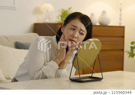 肌トラブルに悩む50代の女性 夜のリビング 肌トラブルに悩む50代の女性 夜のリビング 123560344