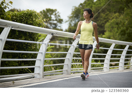 young asian woman jogger walking outdoors 123560360