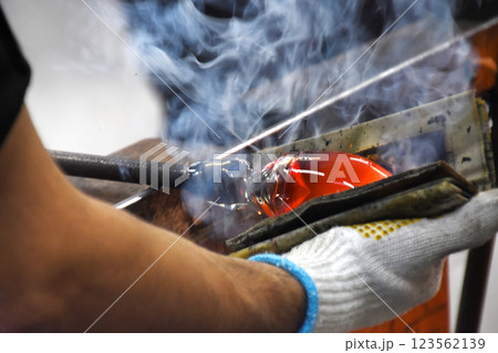 薩摩切子ガラス工場の吹きガラスの形を整える 123562139