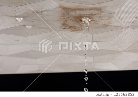 Ceiling Water leak from rain or broken pipe. House Water leaking on ceiling tile board and create dirty stain of flowing water, black background isolated 123562852