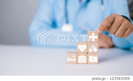 Health insurance concept, Health and access to welfare health concept, Doctor hand holding wooden stacking with healthcare medical and hospital icons on table, Plus sign on block. Health insurance concept, Health and access to welfare health concept, Doctor hand holding wooden stacking with healthcare medical and hospital icons on table, Plus sign on block. 123563509