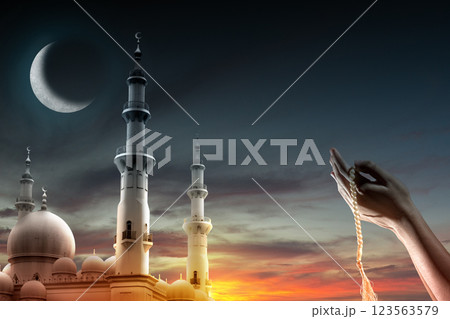 Muslim man praying with prayer beads and mosque with a crescent moon in the night scene background. Copy space or mockup. Concept of Eid Al Fitr and Ramadan Mubarak. Ramadan kareem background Muslim man praying with prayer beads and mosque with a crescent moon in the night scene background. Copy space or mockup. Concept of Eid Al Fitr and Ramadan Mubarak. Ramadan kareem background 123563579