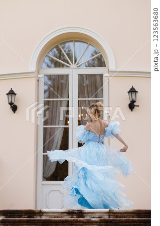 Elegant Woman in a Flowing Blue Gown Walking Down the old stone Stairs 123563680