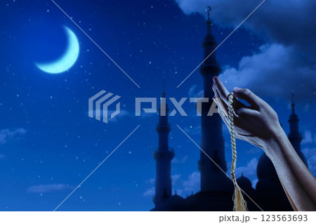 Muslim man praying with prayer beads and a silhouette of the mosque and a crescent moon in the night scene background. Concept of Religion, Spiritual or Ramadan Muslim man praying with prayer beads and a silhouette of the mosque and a crescent moon in the night scene background. Concept of Religion, Spiritual or Ramadan 123563693