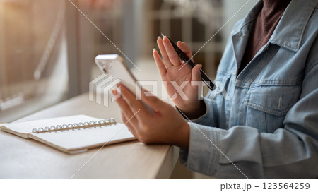 Close up of the left hand holding smartphone with right hand holding a pen and waving to the screen Close up of the left hand holding smartphone with right hand holding a pen and waving to the screen 123564259