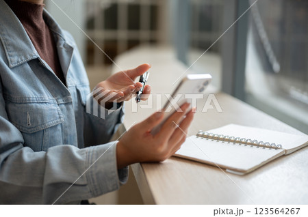 A close up of the right hand holding smartphone and left hand holding a pen with open palm. 123564267