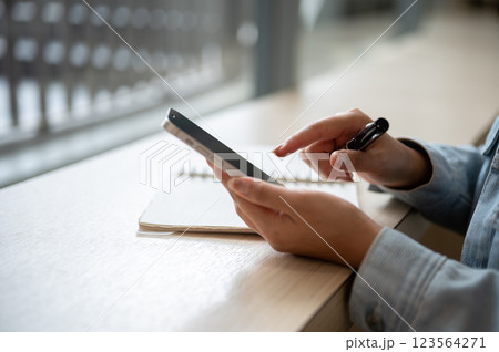A close up of the left hand holding smartphone and right hand pointing at the phone screen. A close up of the left hand holding smartphone and right hand pointing at the phone screen. 123564271