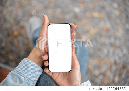 A close up shot of the pair of hand holding white screen smartphone while sitting cross legged. 123564285