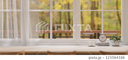 The long wooden table beside large windows and curtain, with the beautiful garden or forest view. 123564386
