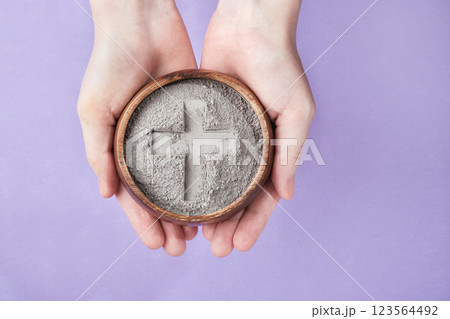 Hands with gray ash bowl on purple background. Ash Wednesday Hands with gray ash bowl on purple background. Ash Wednesday 123564492