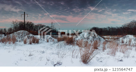 Snow blankets mounds while sun rises, casting warm colors across winter landscape near railway area Snow blankets mounds while sun rises, casting warm colors across winter landscape near railway area 123564747