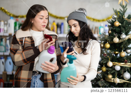 Young girls scanning QR-code on cleaning spray in store during Christmas Young girls scanning QR-code on cleaning spray in store during Christmas 123566111