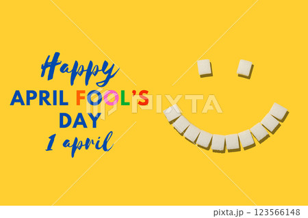 April Fool's Day, smile made from refined sugar cubes on a yellow background, top view, with text 123566148