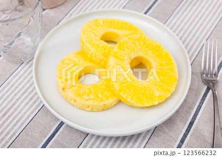 On table there is plate with summer dessert - round pieces of pineapple pulp. On table there is plate with summer dessert - round pieces of pineapple pulp. 123566232
