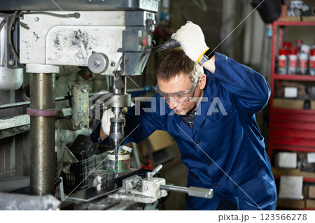 Experienced machinist using drill press in industrial metal workshop Experienced machinist using drill press in industrial metal workshop 123566278