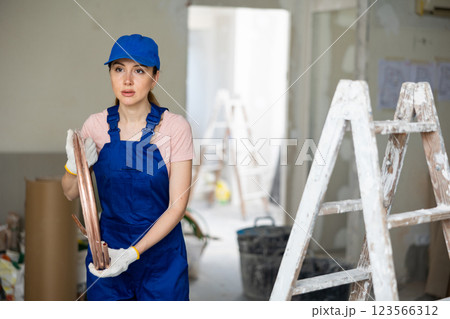 Female builder carrying conduit at renovating object Female builder carrying conduit at renovating object 123566312