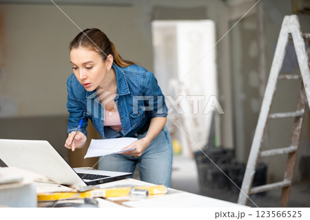 Owner of cottage checks the completion of repair work using laptop 123566525